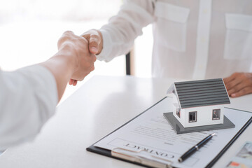 Estate agent in suit sitting in an office desk shaking hands with customer after contract signature accept agreement finish buying or rental real estate for transfer right of property.