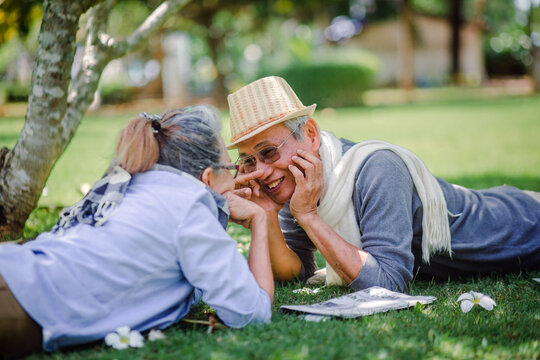 Romantic happy senior couple. lying elderly resting and teasing each other on green grass in the park. Love is everything, image no focus..Retirement age concept and love, copy space for text