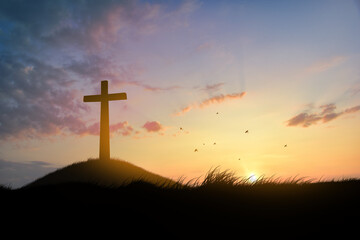 Concept conceptual black cross religion symbol silhouette in grass over sunset or sunrise sky