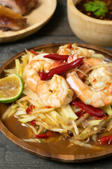 Papaya salad with pickled fish soup and shrimp in wooden table on wooden table.