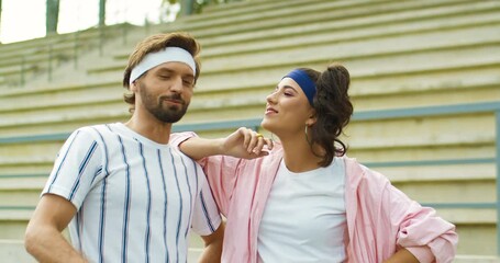 Couple of happy funny vintage man and woman talking on street and smiling. Portrait of handsome Caucasian male and beautiful girl chatting while looking at each other outdoor in good mood. 70s concept