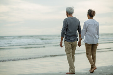 Senior couple having talk while Walking the beach together .on beach at evening,.Retirement age concept and love and Lifestyle Healthy Travel , copy space for text