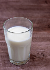 Leche en vaso de vidrio transparente sobre base de madera 
