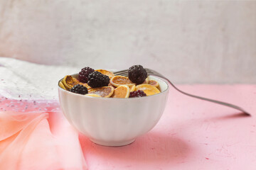Mini pancakes with blackberry white dishes on a pink table. Lovely breakfast, morning light. A new trend dessert in social networks. Little Dutch poffertjes. Top view, flat lay.