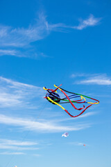 Long tailed red, black, blue & yellow kite flying above depok Beach at the Jogja air show in yogyakarta, Indonesia