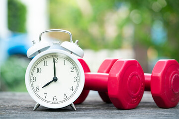 Time for exercising clock and dumbbell on the table outdoor, sport and healthy concept