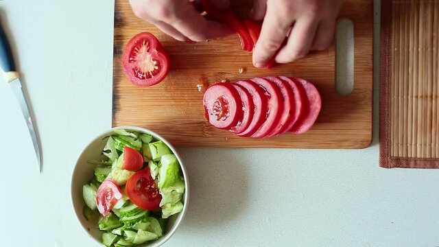 The process of preparing healthy food. Slicing tomato for salad.