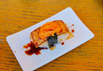 Salmon and cheese burned sushi, on white dish and brown table