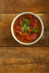 Gray dish of vegetable soup on a wooden table.