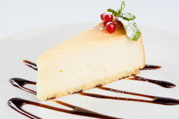 A piece of classic cheesecake with a berry on a white plate. new york cheese cake.
