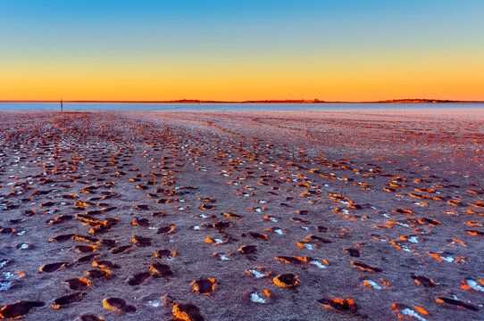 Sunset on Lake Ballard. Footprints in the mud show the tracks of people. with salt crystals forming in the imprint.
