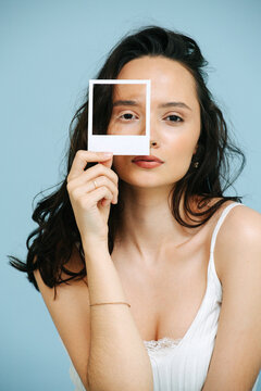 Portrait of beautiful woman holding frame over eye with vitiligo eyelashes.