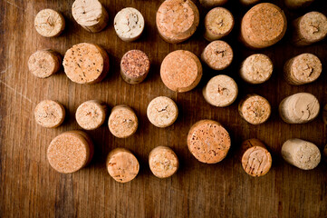 Wine corks of different sizes, standing upright on an old wooden surface. Background for liquor.