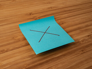 A paper sticker pasted on a wooden surface with the image of the multiply symbol
