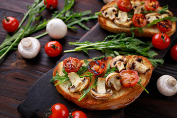 Tasty homemade Italian antipasti bruschetta with chopped tomatoes, champignons and arugula, healthy and delicious snack close up