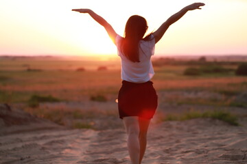 a girl alone in nature at sunset enjoys freedom and nature, happiness in the fresh air, psychological freedom and happiness