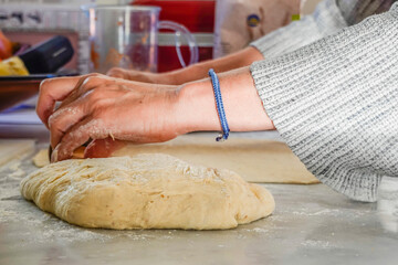A woman rolls dough to make  home-made pizza