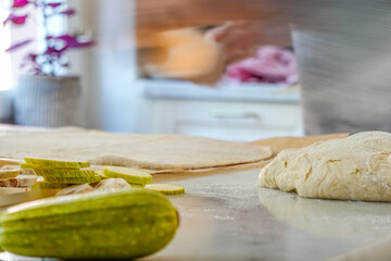 A woman rolls dough to make  home-made pizza