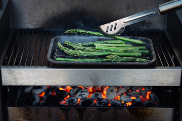 Grüner Spargel zum Grillen, barbecue mit Olivenöl, Kräutern und Gewürzen auf dem Grill, Draufsicht. Gesunde Ernährung Konzept, vegan. Selektive Schärfe