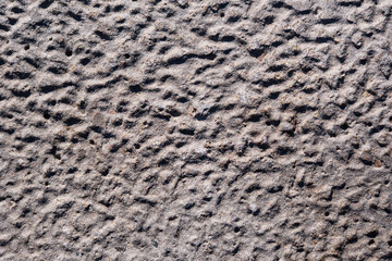 Texture of uneven concrete surface painted in warm color, wavy surface, seamless pattern. Natural stucco pattern, urban exterior