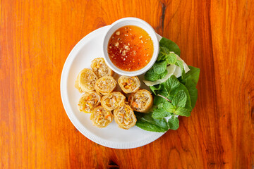 Deep fried spring roll on a white plate on a wooden table