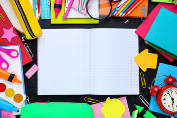 Different school supplies with blank sheet of paper on blackboard