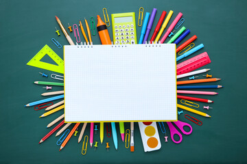 Different school supplies with blank sheet of paper on green chalkboard