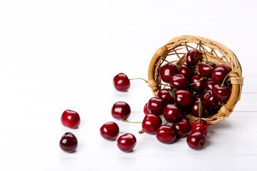Sweet cherries in basket on white wooden table