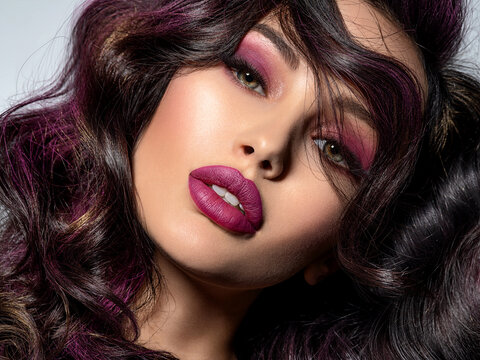 Portrait of beautiful young woman with bright maroon makeup. Beautiful brunette with bright cherry lipstick on her lips. Pretty girl with long black hair. Brunette with brightly colored hair.