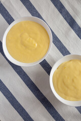 Homemade vanilla custard pudding in white bowls, overhead view. Flat lay, top view, from above.