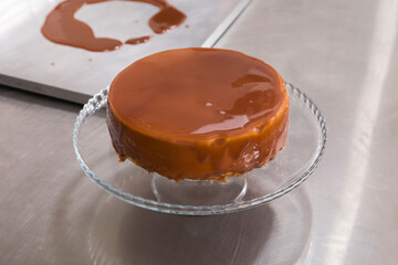 Freshly made cheesecake on a glass stand.