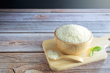 Jasmine rice in wooden cups and wooden spoons on a wooden tray on wooden table.