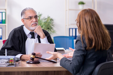 Old male judge and female client in the office