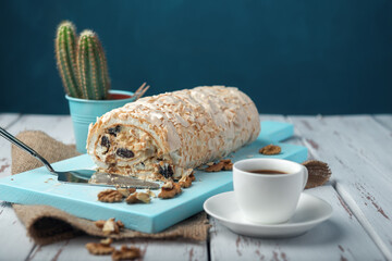 A cup of coffee meringue roll on a white vintage wooden kitchen table with burlap napkin.