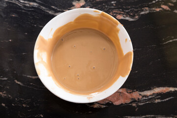 Melted hot chocolate in a white plastic bowl.
