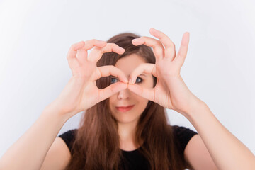 Girl in a black T-shirt with long hair grimaces and shows glasses with her hands isolated on a white background. The concept of an emotional portrait.