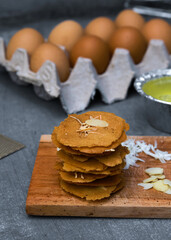 Almond crispy cheese on wooden board surounded by the ingredients such as eggs, cheese, chopped...