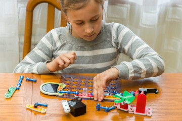 Positive lady playing with toy. She making it from constructor. Entertainment concept. Education, children, technology, science and futuristic concept. E-learning.