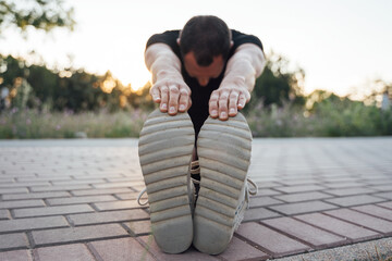 Male runner trying to stretch his legs before running outdoors