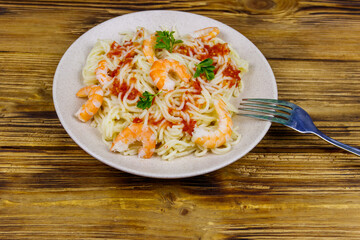 Spaghetti pasta with prawns, tomato sauce and parsley on wooden table