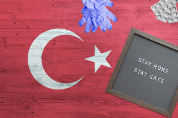 Turkey flag background on wooden table. Stay Home writing board, surgery gloves, pills with minimal national Covid 19 concept.