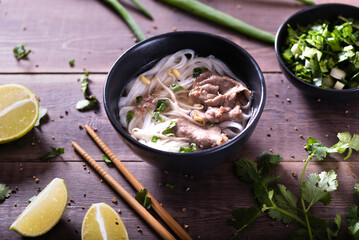 Asian cuisine, Vietnamese pho bo soup in a black plate on a wooden background
