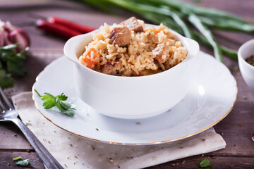 Pilaf - traditional Eastern dish made with rice, vegetables and meat. Asian food. The concept of oriental cuisine , on a wooden table