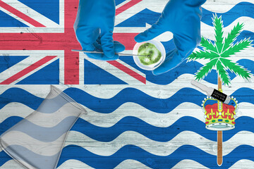 British Indian Ocean Territory flag on laboratory table. Medical healthcare technologist holding COVID-19 swab collection kit, wearing blue protective gloves, epidemic concept.