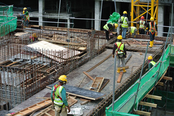 Construction workers fabricating steel reinforcement bar at the construction site in Malacca, Malaysia. The reinforcement bar was tied together using tiny wire.  