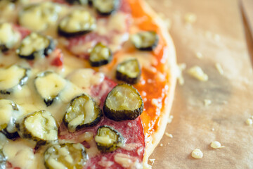 Simple homemade pizza with pickled cucumber cheese, sausages and cheese. Selective focus. Shallow depth of field. 
