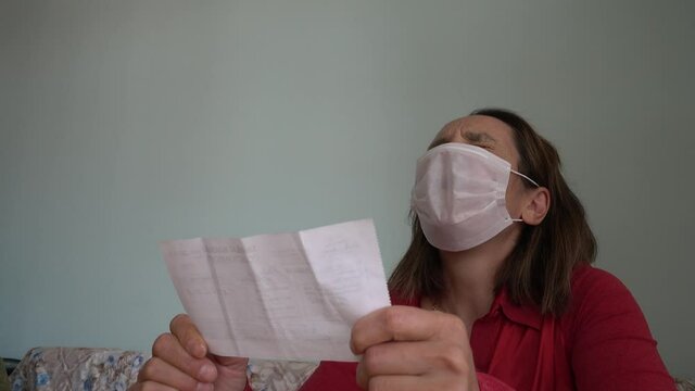 Fethiye, Turkey - 20th of May 2020: 4K Lockdown reality - Business woman in mask reads a payable note and drops her head
