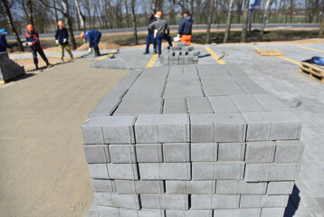 A large pallet with paving slabs, workers are building a parking lot for cars.
