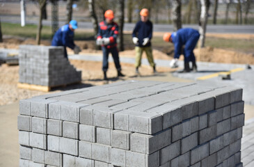 Pallet with paving slabs, workers lay out a pedestrian road.
