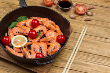 Shrimp tiger prawns with tomatoes and lemon in pan.